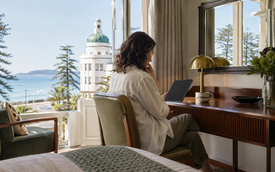 22BET promo code: an adult examining a tablet at a quiet desk in a coastal New Zealand apartment
